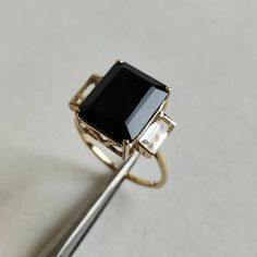 ITEM DESCRIPTION: >> The Ring is made from Solid 14K Yellow Gold. Gemstone used is absolutely natural and ethically sourced. >> Natural White Topaz and Black Onyx in prong setting is studded on it with utmost precision. >> This is a minimalist design which makes it a hassle free and everyday jewelry. >>Center Gem: Black Onyx Center Gem size: 12x10 mm Center Gem weight: 4.95 ct >>Side gemstone: White Topaz Side Gems size: 6x3 mm Gem weight: 1.05 carats Gold purity: 14K (58.33% approx.) Gold weigh Black Sapphire Ring In 14k Gold, Formal Black Sapphire Ring In 14k Gold, 14k Gold Black Gemstone Rings, 14k Gold Black Ring With Center Stone, Black 14k Gold Ring With Center Stone, Black Emerald-cut 14k Gold Jewelry, Black Onyx Jewelry, Onyx Jewelry, Black Onyx Ring