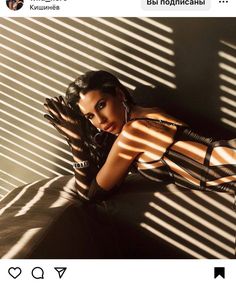 a woman laying on top of a bed next to a window with blinds behind her