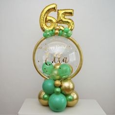 a gold and green balloon filled birthday cake with the number 55 on it's top