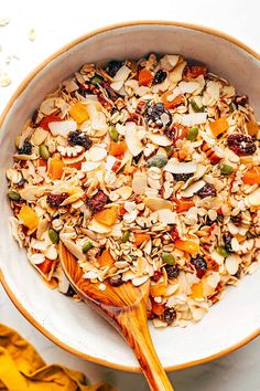 a bowl filled with granola and nuts on top of a white table next to yellow leaves