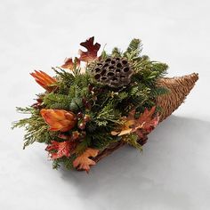 an arrangement of foliage and flowers on a white surface