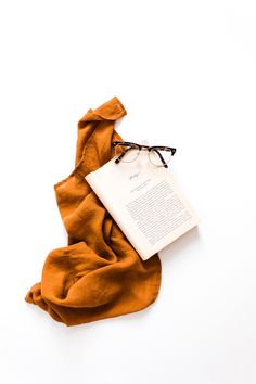 an open book with glasses on top of it next to a pair of eyeglasses