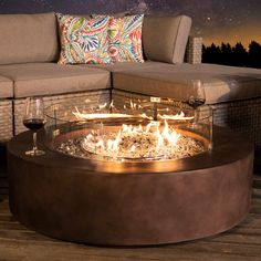 a fire pit sitting on top of a wooden floor next to a couch and table