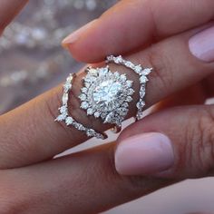 a woman's hand holding an engagement ring with diamonds on it and a diamond set in the middle