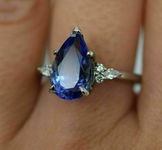 a woman's engagement ring with an oval blue sapphire and three diamond sidestones