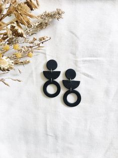 two black earrings sitting on top of a white cloth