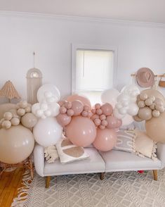 balloons are arranged on the back of a couch in a room with white walls and wood floors