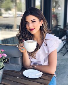 a woman sitting at a table with a coffee cup