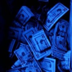 a bag full of money sitting on top of a blue tablecloth covered in dollar bills