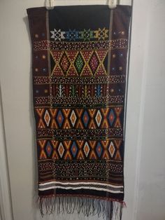 a wall hanging on the side of a door with an ethnic design and fringes