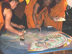 the monks are doing something to paint on the table