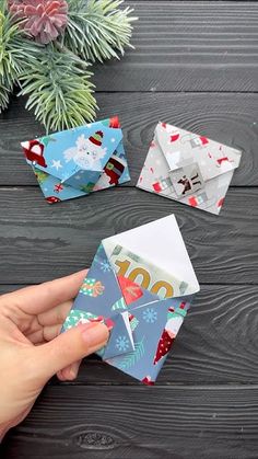 someone is holding an origami envelope in front of some christmas decorations on a table