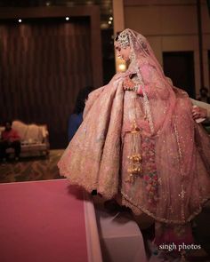 a woman in a pink wedding dress and veil standing on a stage with other people