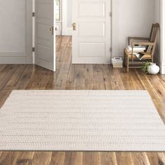 an open door in a white room with wooden floors and hard wood flooring on the side