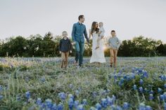 a group of people walking through a field with blue flowers