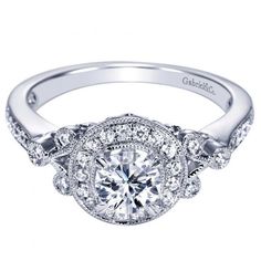 a white gold engagement ring with an intricate halo setting and round diamonds on the band