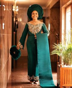 a woman in a green dress is walking down the hallway