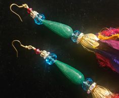 These wild sari silk distressed pierced earrings will bring out the bohemian in you! 14" of highly distressed, raw sari silk ribbons are suspended from a shiny gold tone tulip bead cap. The actual earring beads include faceted crystals, rhinestone rondelles, emerald green agate teardrops and gold tone tribal metal spacers. The total length of the earring from the wire to the very bottom is 18-19". These are fairly lightweight, but you can trim the silk ribbons to your preferred length if desired. See my other listings for the complementary sari silk chest piece! From the Atelier of Kat Kouture. Bohemian Danglers With Latkans For Festive Occasions, Gold Bohemian Tassel Earrings For Festive Occasions, Bohemian Green Earrings For Celebration, Traditional Gold Tassel Festival Earrings, Traditional Gold Tassel Earrings For Festivals, Elegant Multicolor Latkans Tassel Earrings, Bohemian Handmade Danglers For Party, Festive Tassel Earrings For Festivals, Bohemian Green Danglers For Party