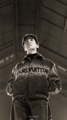 a young man standing on top of a snowboard wearing skis and holding his hands in his pockets