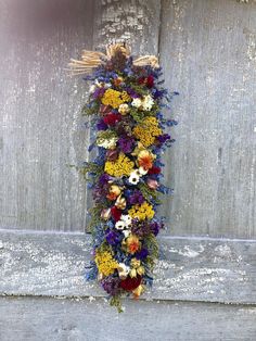 a bunch of flowers that are on the side of a wooden wall with some grass