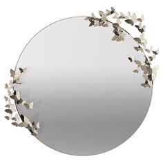 a round mirror with silver leaves on it