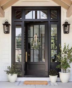 an image of a black front door with potted plants