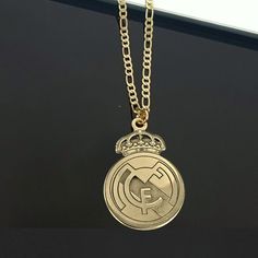 a close up of a gold necklace with a soccer ball on the front and a crown on the back