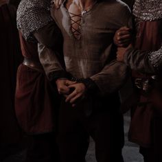 two men dressed in medieval clothing standing next to each other with their arms around one another