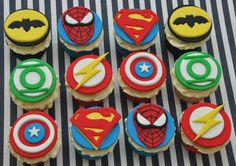 cupcakes decorated like superheros are on a striped tablecloth