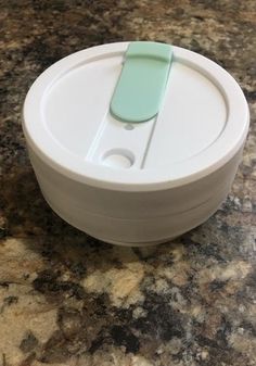 a white container with a green lid sitting on top of a counter