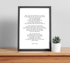 a framed print with a poem on it next to a potted plant