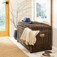 a wicker bench with a hat, sweater and slippers on it in front of a window