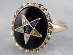 This Order of the Eastern Star ring features gorgeous enameled details amongst the bold black onyx backdrop. Crafted of yellow gold this vintage ladies' piece is in wonderful condition with a perfect polish! Metal: 10K Yellow GoldGem: Black OnyxGem Measurements: 12.3 x 9.6 mm, OvalMaterials: White, Yellow, Blue, Red, and Green EnamelRing Size: 4.50Marks: “BDA 10K” Stamped on the inside band Order Of The Eastern Star, Eastern Star, Ladies Ring, Black Onyx Ring, Enamel Ring, Ring Black, Star Ring, Onyx Ring, Green Enamel