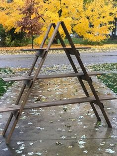 an upside down wooden shelf sitting in the middle of a sidewalk with fallen leaves on it