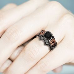 a woman's hand with a black and gold ring on her left hand,