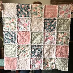 a woman is holding up a quilt made with flowers