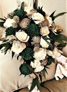 a bouquet of white and green flowers sitting on top of a couch next to pillows