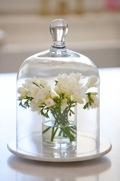 a glass clochel with flowers in it on a table