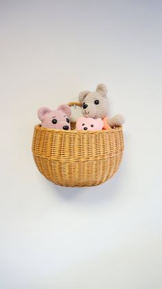 three stuffed animals in a basket on a wall