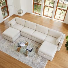 a large sectional couch sitting on top of a wooden floor next to a glass table