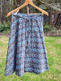 a skirt hanging on a wooden hanger in front of some green grass and trees