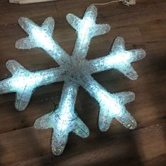 a snowflake made out of plastic on top of a wooden floor