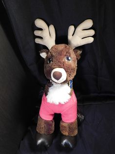 a stuffed reindeer wearing a pink sweater and black boots with its hands on it's hips