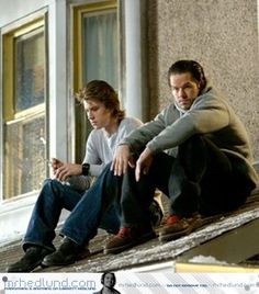 two young men sitting on the ground next to each other