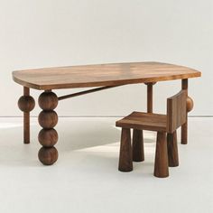 a wooden table with two chairs and a bench in front of it on a white floor