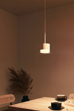 a wooden table topped with a white light hanging from it's centerpiece next to a potted plant