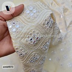 the hand is holding an ivory colored wedding dress with beading and sequins