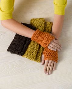 the woman is holding her hands together with crocheted gloves