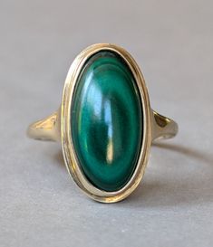 Large Vintage Malachite 9ct gold ring c1978. Beautiful statement ring featuring a large  malachite 18mm x 9mm displaying beautiful circles of green circle formations. The malachite as a fantastic deep green colour and a wonderful pattern that suits the ring shape it is set into a good strong 9ct oval setting and fully hallmarked for 9ct gold Birmingham and the year 1978. The ring is in excellent condition for its age. Total ring face is 20mm x 12mm. Ring Size UK Q U.S  8 the total weight is 5g. Classic Green Cabochon Ring, Green Oval Dome Ring With Polished Finish, Antique Green Oval Cabochon Ring, Antique Green Emerald Ring With Polished Finish, Collectible Green Emerald Ring In 14k Gold, Collectible 14k Gold Emerald Ring, Formal Malachite Gemstone Rings, Yellow Gold Malachite Ring Gift, Oval Malachite Jewelry In Yellow Gold