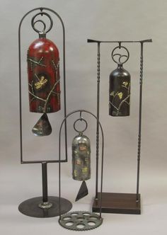 an assortment of metal items on display with white background in back ground, including two red and one black fire extinguisher